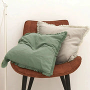 Cushion cover set of 2 with tassels; sage green and light gray fringe pillows on a brown chair.