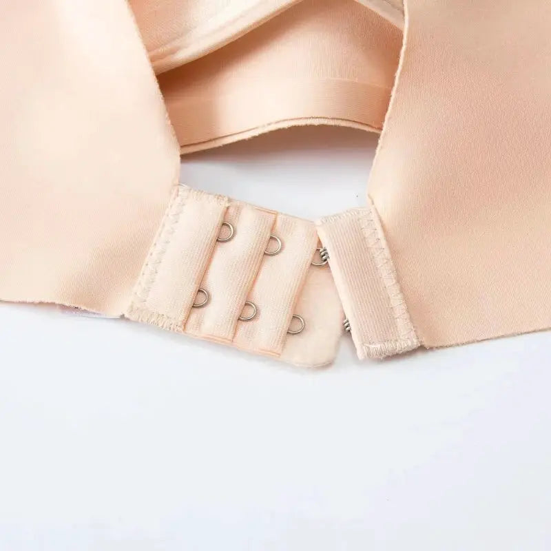 Seamless women's bra in peach nude with back hook closure and three-row fasteners; soft fabric.