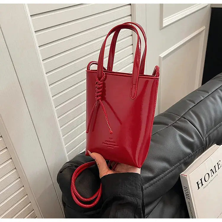 Red PU leather mini crossbody bag for women with two top handles and decorative cord tassel.