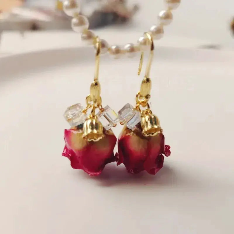 Pair of red rose epoxy resin drop earrings featuring natural rose petals, crystal beads, and gold-tone caps