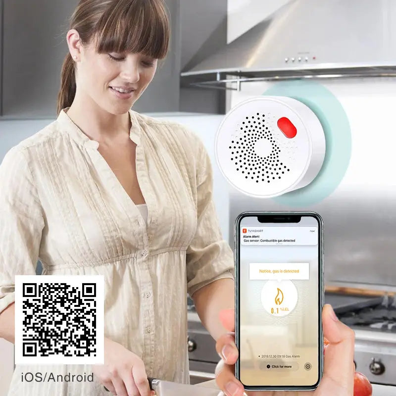Tuya Smart Home WiFi Natural Gas Sensor, white circular detector with red indicator beside a smartphone alert in the kitchen.