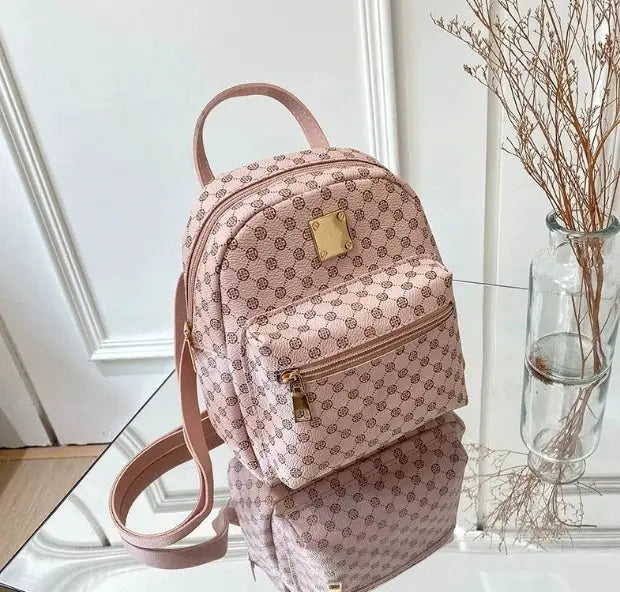 Backpack pink patterned with gold hardware, front zip pocket, top handle and adjustable straps