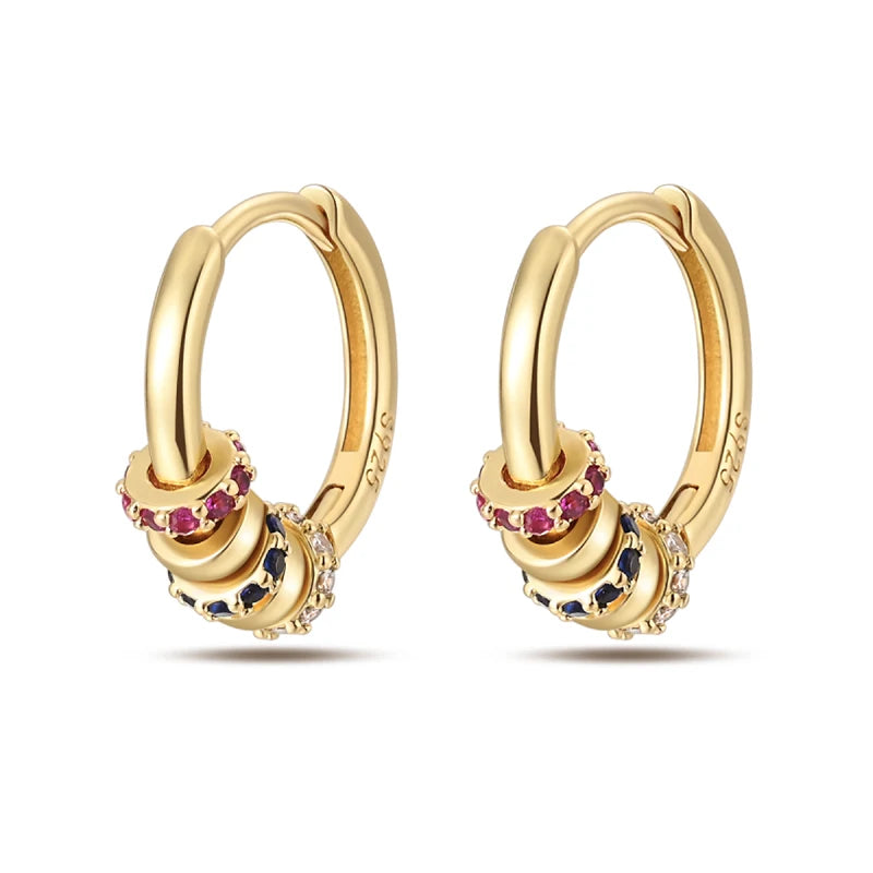 Gold-tone hoop earrings pair with stacked rings and multicolor gemstone accents
