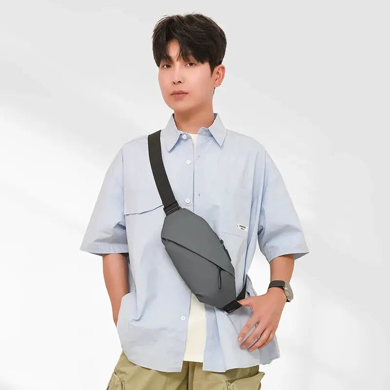 Men's minimalist gray crossbody waist bag worn diagonally across the chest with a black strap.