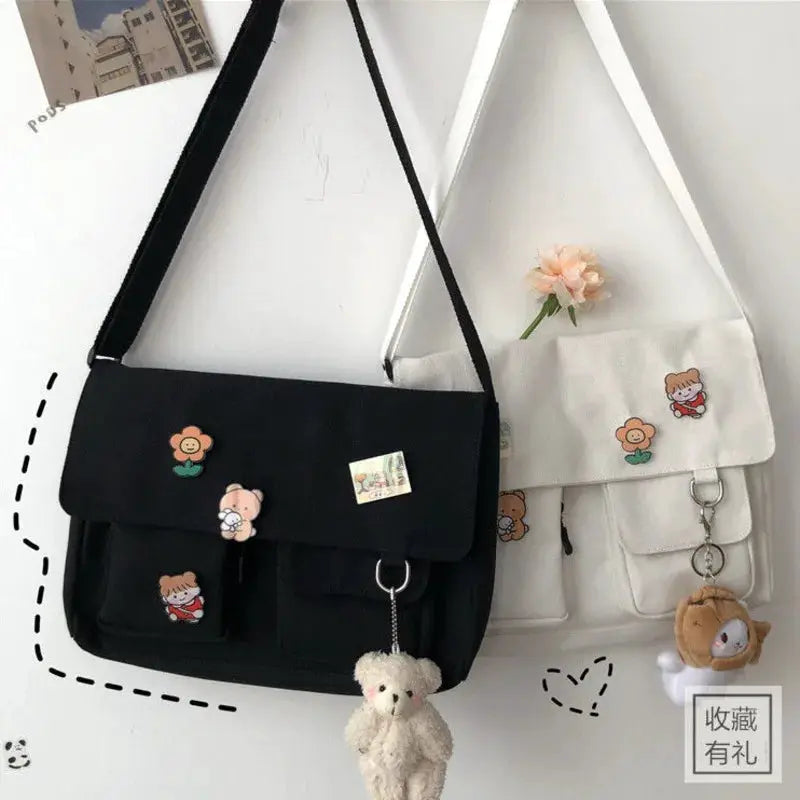 Two canvas messenger bags in black and white with cute cartoon patches and teddy keychain