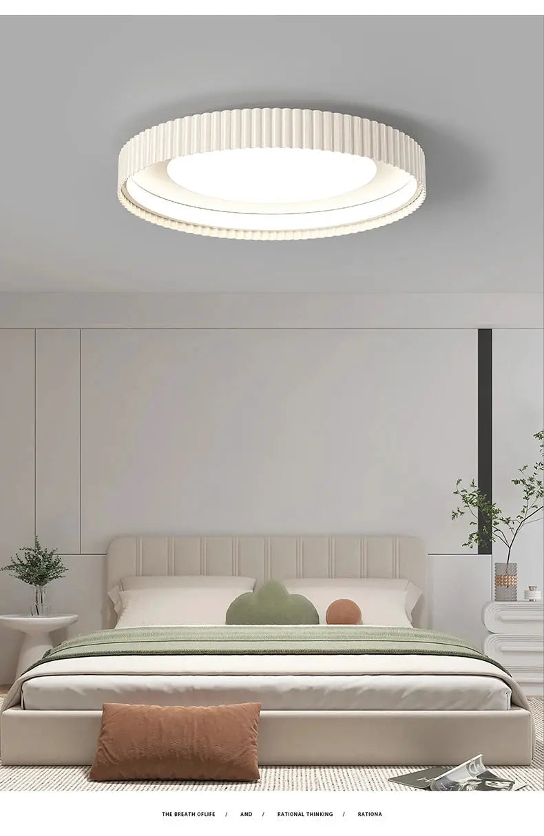 Simples Market modern round LED ceiling light with ribbed white metal ring, over a beige bedroom bed.