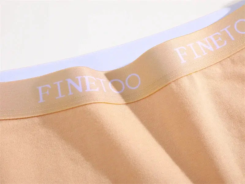 FINETOO cotton women's underwear waistband close-up; peach low-rise briefs with white branded elastic.