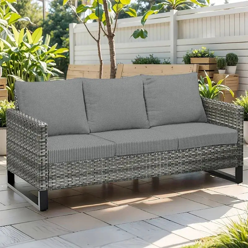 Outdoor patio sofa in grey wicker with six cushions, three seat and three back cushions, on tiled deck