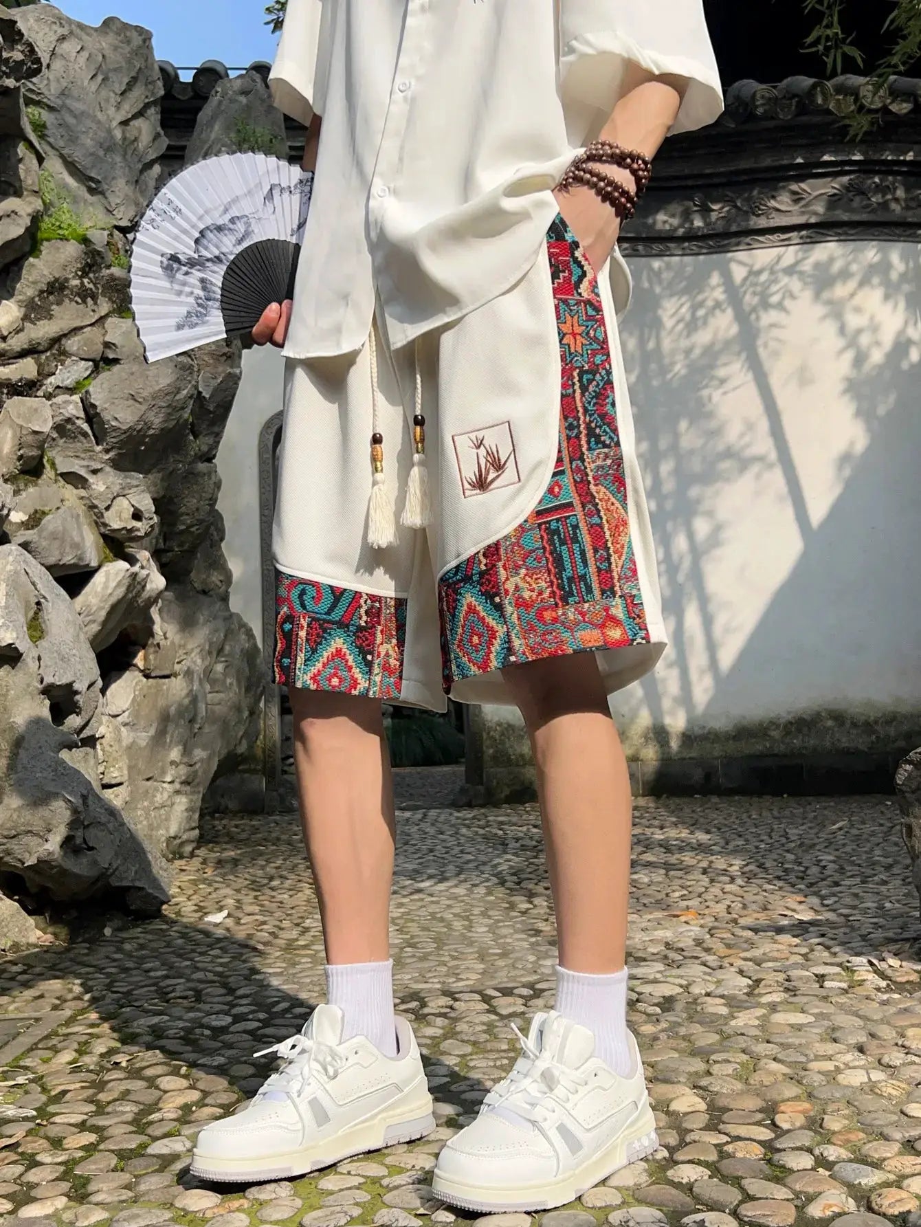 Men's white Simples Market embroidered shorts with colorful geometric side panels and pockets.