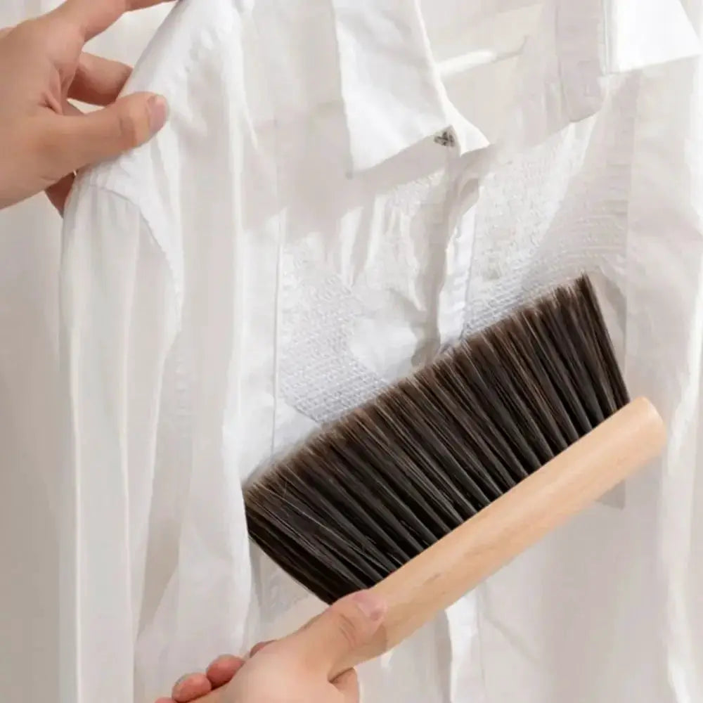 Natural wood bristle brush with light wooden handle used on a white shirt.