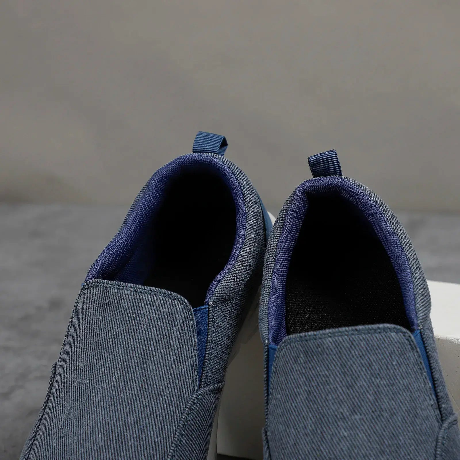 Pair of men's blue denim canvas slip-on sneakers, breathable casual walking shoes.