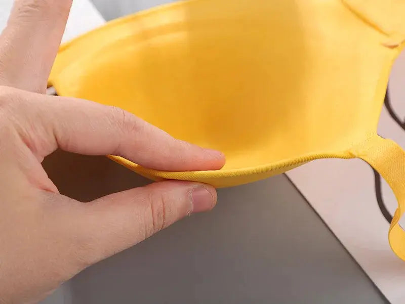Women’s yellow seamless bra cup held in hand, no-wire breathable fabric