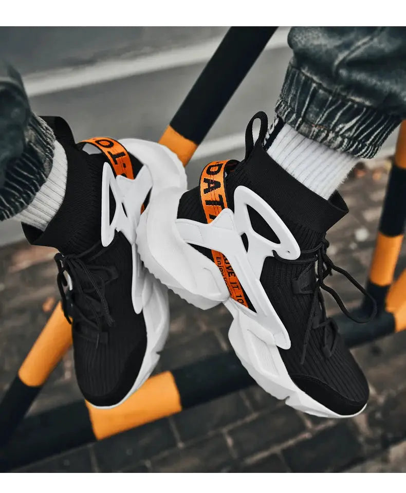 Pair of men's black and white knit sneakers with chunky white soles and orange pull tabs.