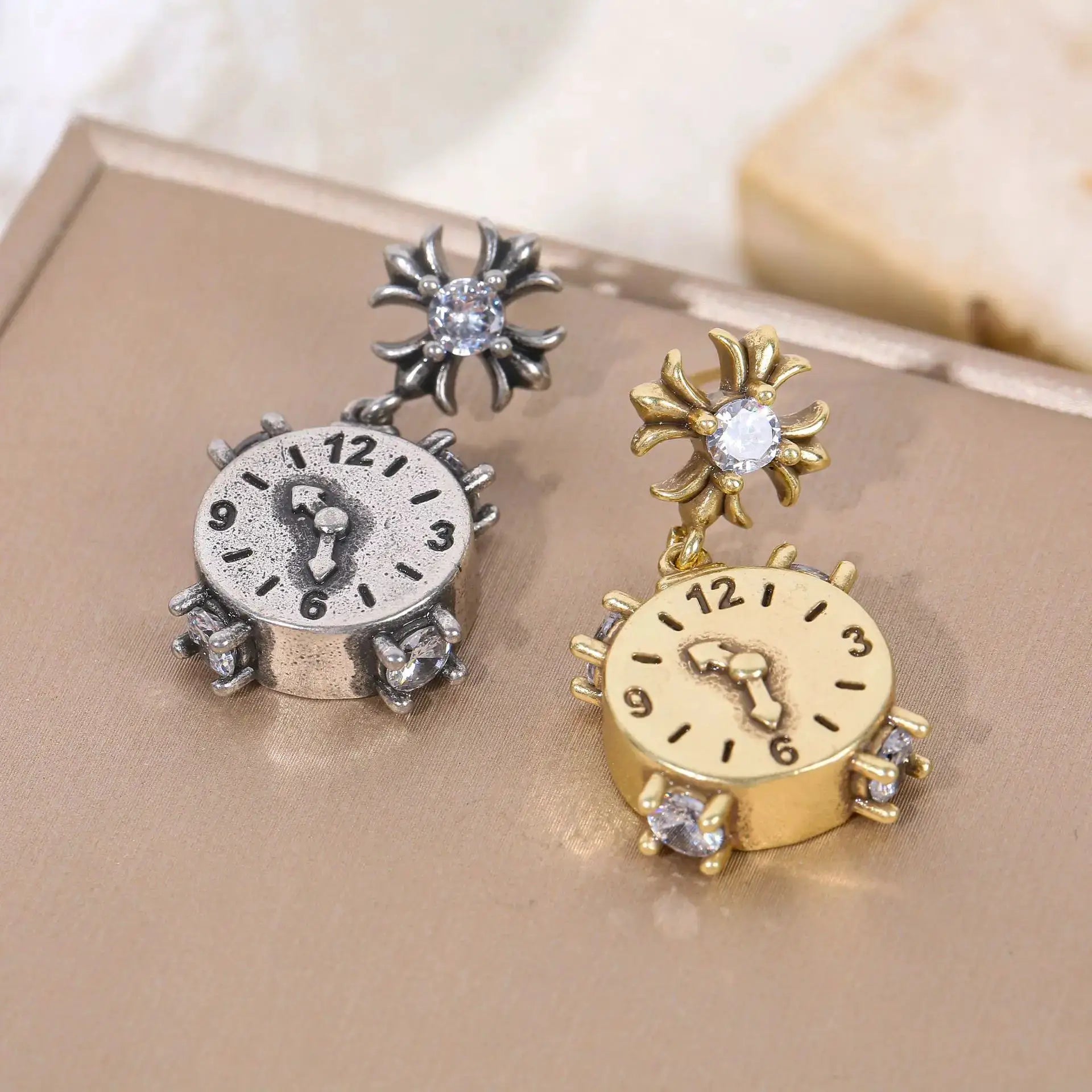 Unique clock earrings in silver and gold tones with crystal centers; two-piece set with sunburst around the dial.
