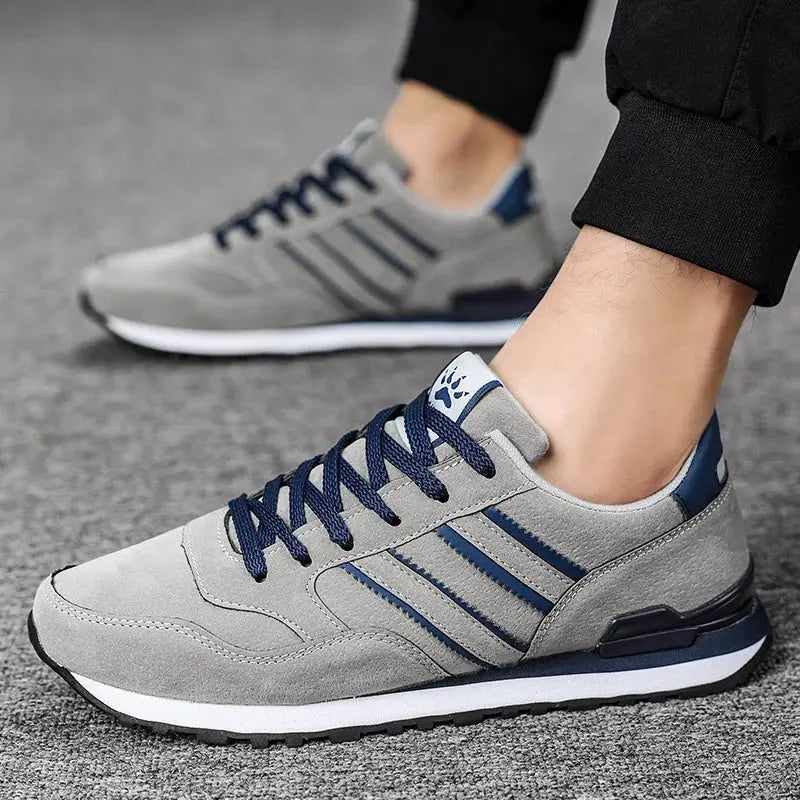 Pair of gray artificial leather men's casual sneakers with navy laces and blue side stripes