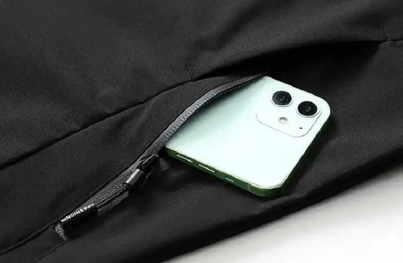 Men's lightweight waterproof rain jacket with hood in black; zippered pocket holding smartphone