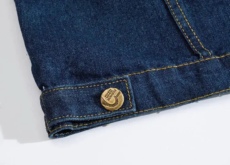 Denim jeans vest close-up in blue indigo with yellow stitching and a gold button.