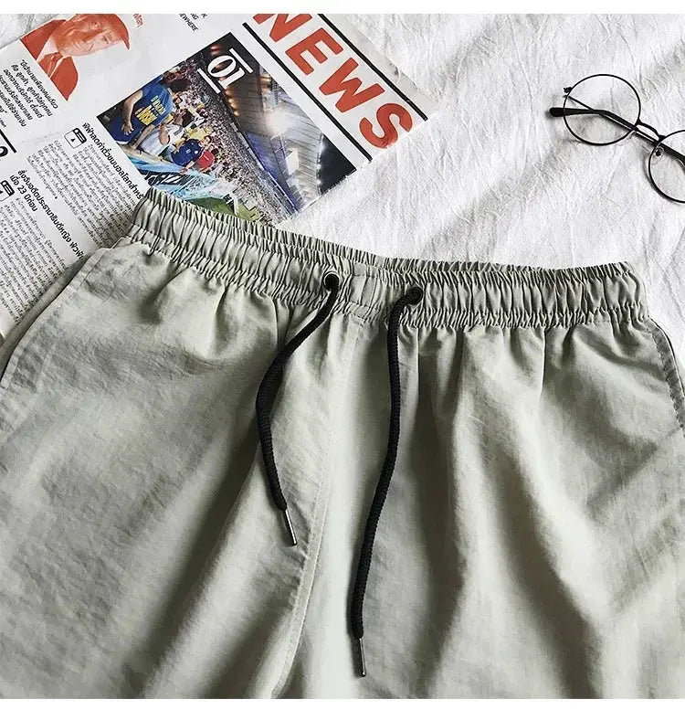 Men's light gray swim shorts with black drawstring and elastic waistband
