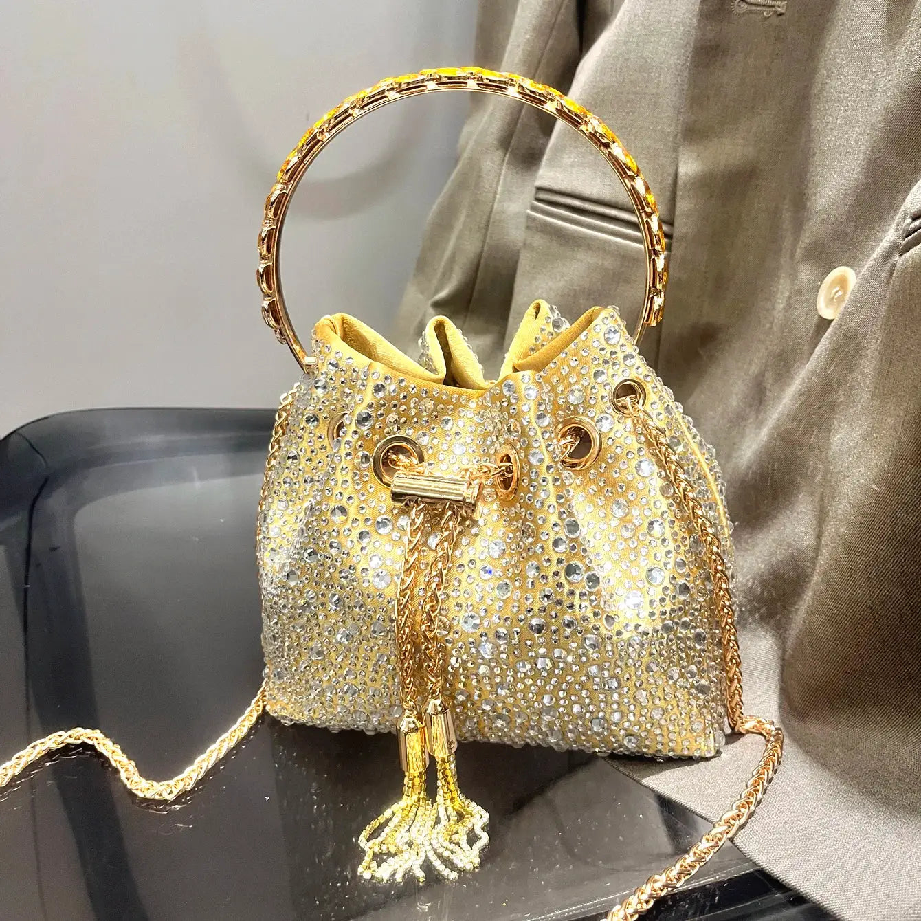 Gold rhinestone evening clutch by Simples Market with crystal studs, round ring handle and gold chain strap