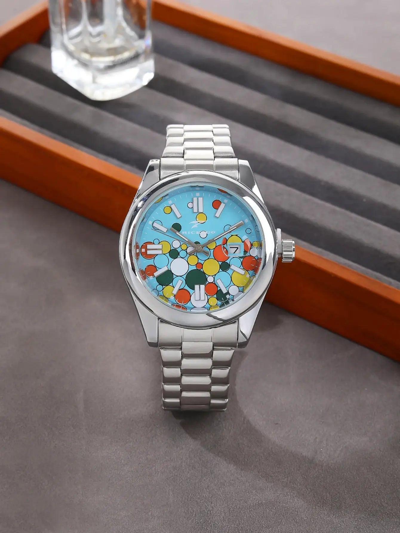 Classic men's quartz watch with a silver stainless steel band, blue dial with colorful dot pattern and date window.