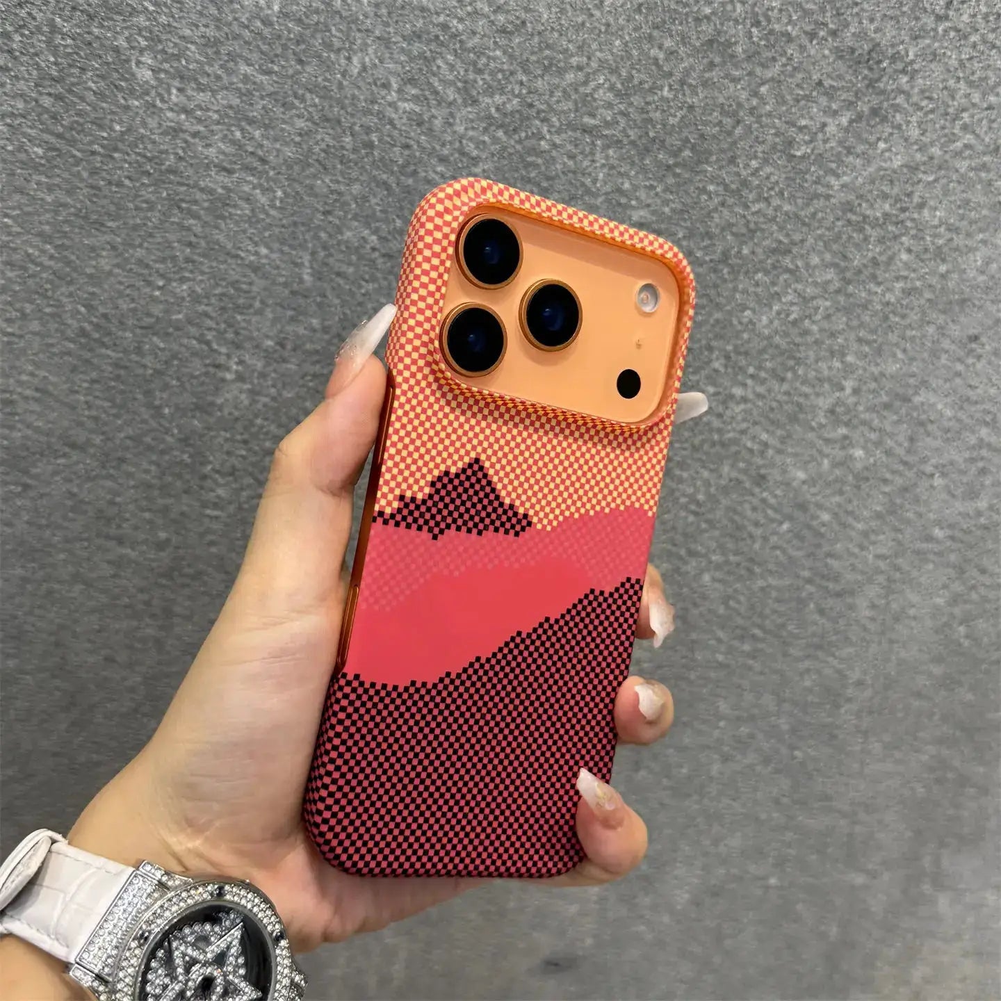 Frameless carbon fiber Kevlar MagSafe iPhone case with orange-pink gradient checkerboard pattern