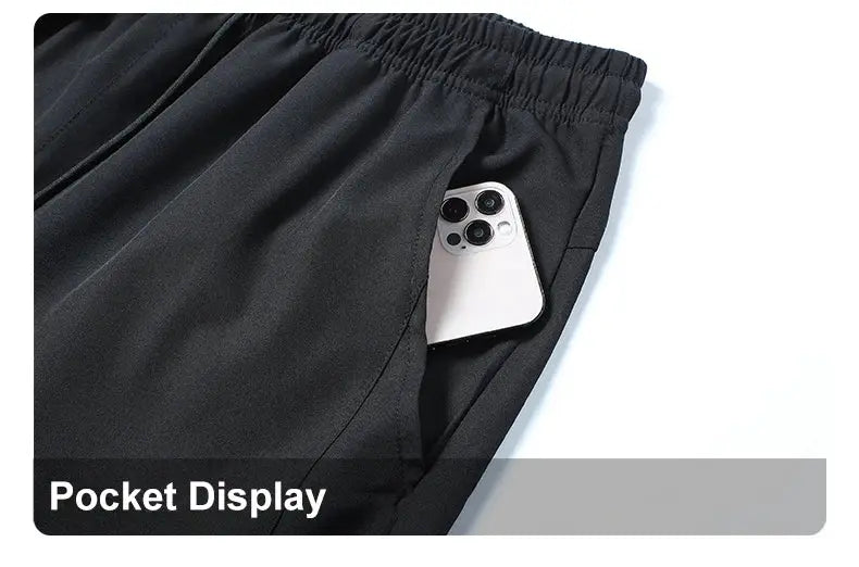 Running pants with a phone in the side pocket, black fabric, elastic waistband.