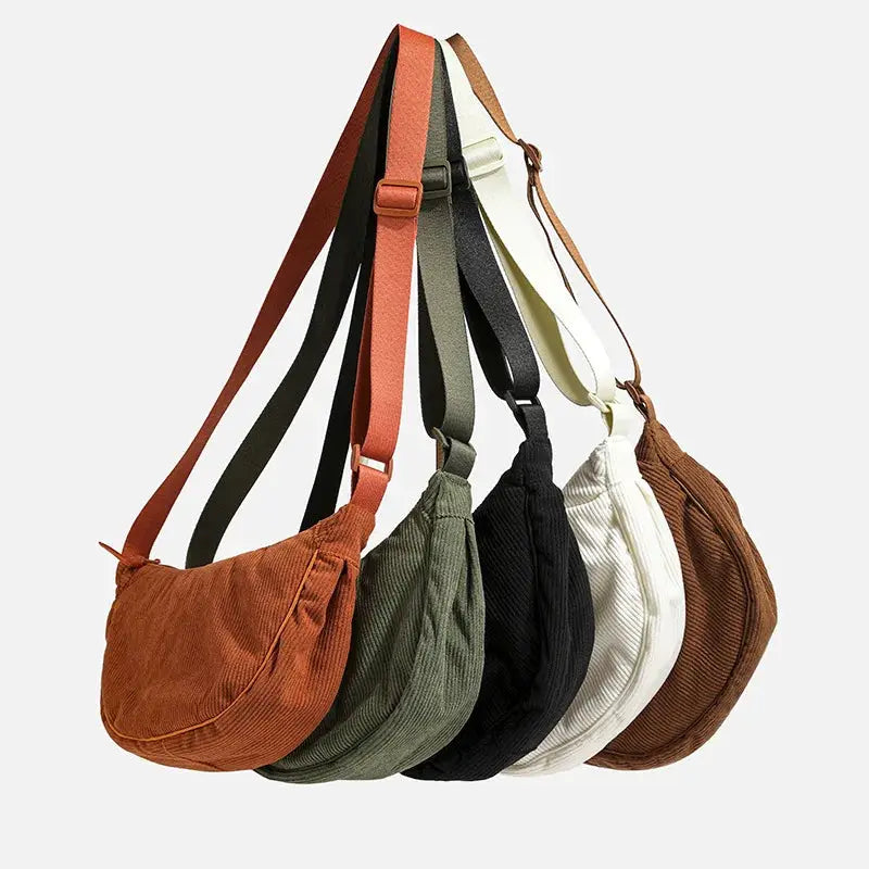 Six solid-color corduroy hobo shoulder bags with long straps in rust, olive, black, cream, white, and brown.