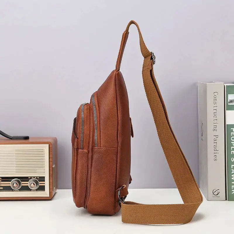 Simples Market brown genuine top-grain leather chest bag with tan crossbody strap and zip pockets.