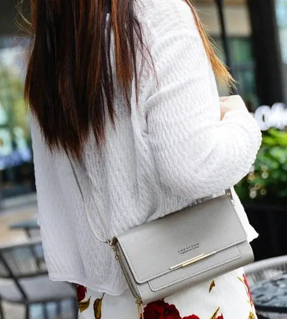 Women's mid-size wallet bag in light gray faux leather with crossbody strap and gold-tone hardware.