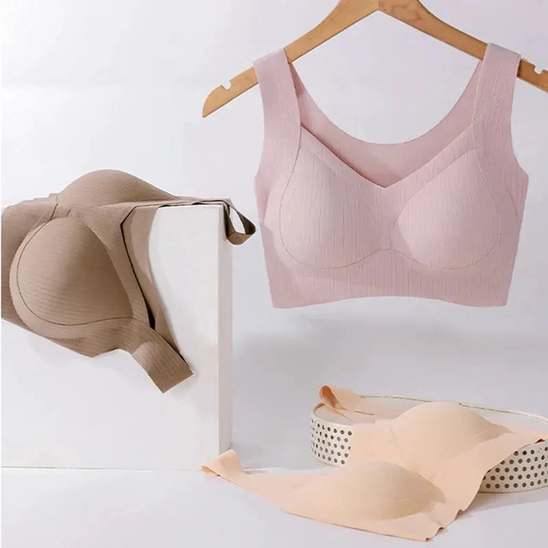Pink wireless one-piece bra with fixed cups and back-smoothing vest style, displayed with beige undergarments