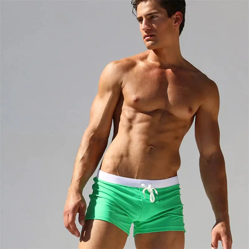 Men's green swim trunks with white drawstring waistband, boxer-style quick-drying beach shorts.