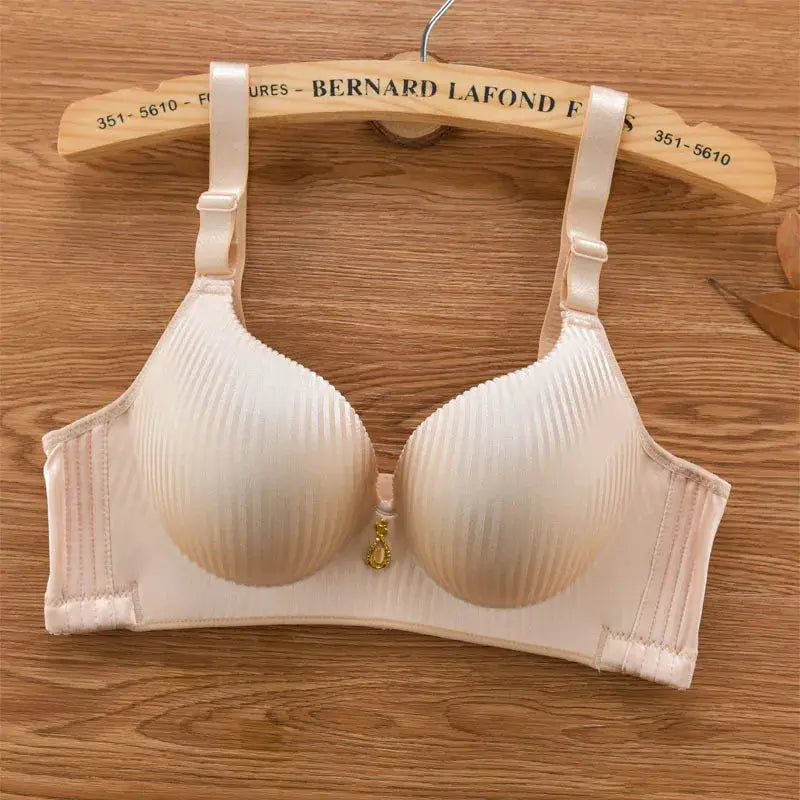Beige padded bra with adjustable straps and a small gold charm between cups on a wooden hanger