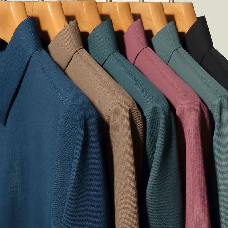 Seven men's short-sleeve solid-color polo shirts in assorted colors on wooden hangers.