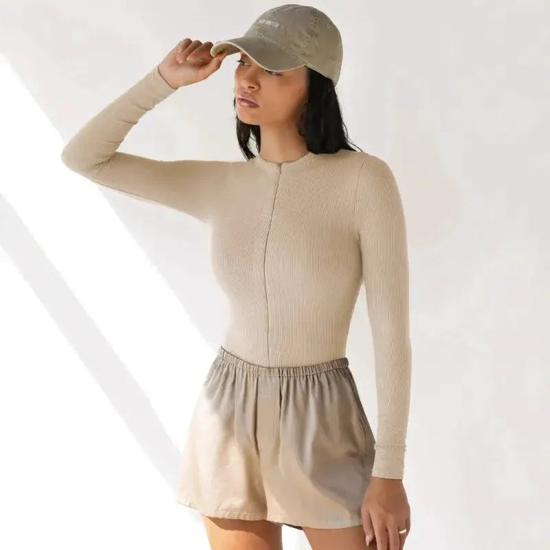 Beige knit jumpsuit with zipper top, tight-fitting long-sleeve one-piece worn by model