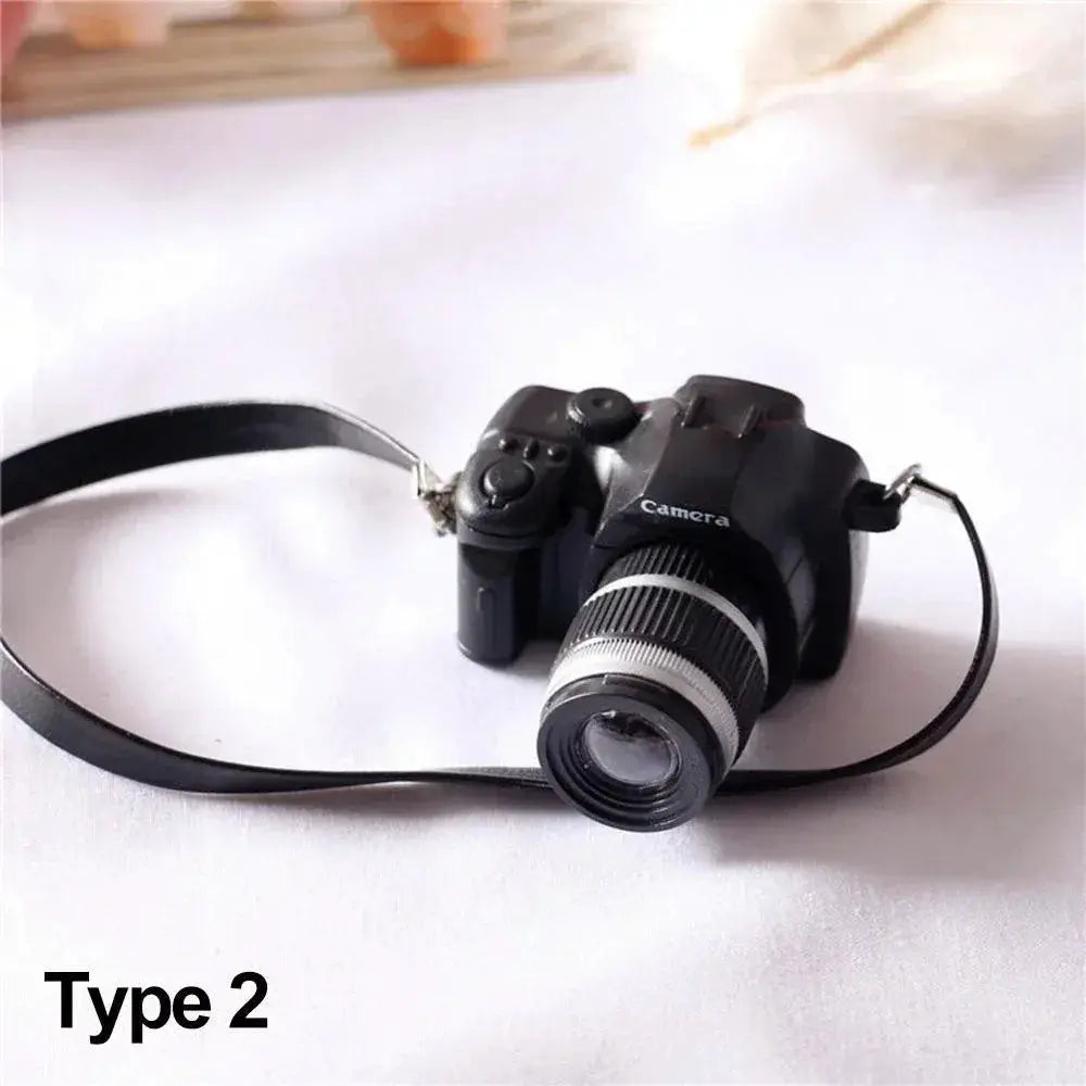 Dollhouse miniature digital SLR camera in black with lens and strap