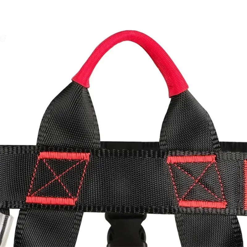 Rock climbing harness by Simples Market; black nylon straps with red stitching and red loop.