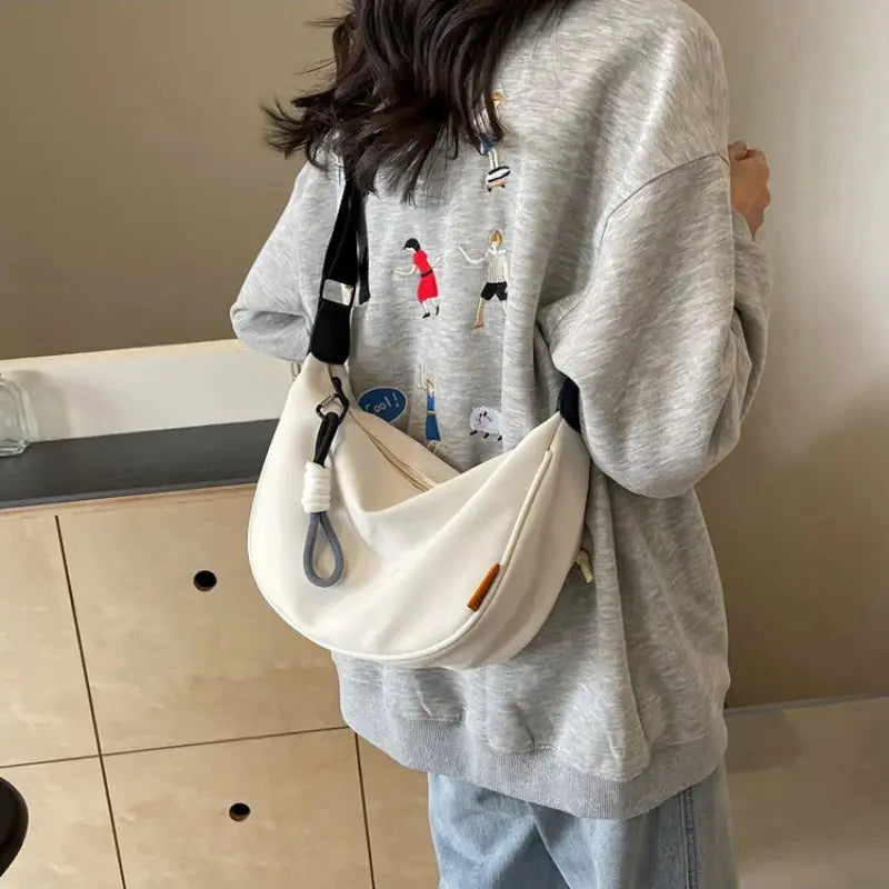 Dumpling crossbody bag, cream with wide black shoulder strap for casual commuting.