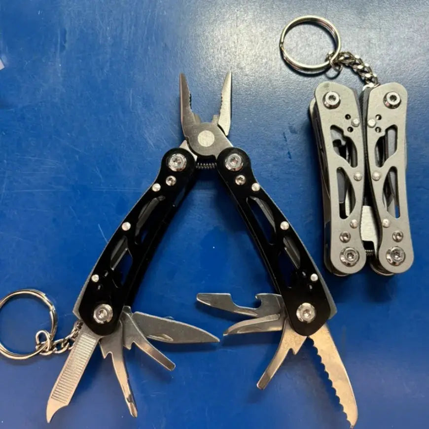 Two multitools: black-handled plier-style survival tool and a silver folding multi-tool on a keychain