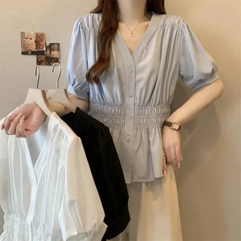 Simples Market light blue V-neck short-sleeve top with smocked waist; white and black tops on hangers.