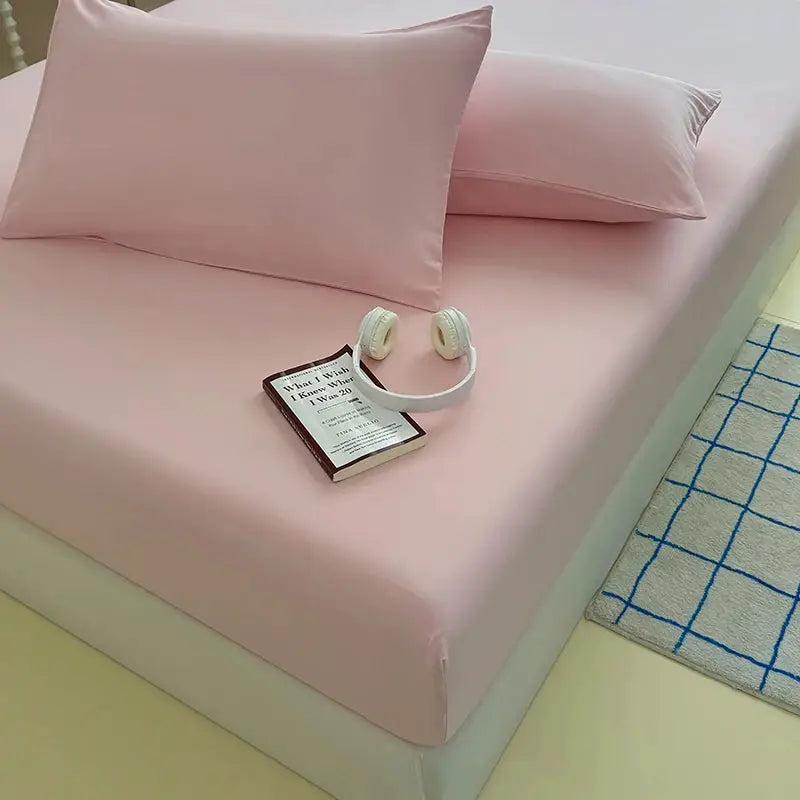 Pink washed fitted sheet with elastic bands on a bed with matching pink pillowcases.