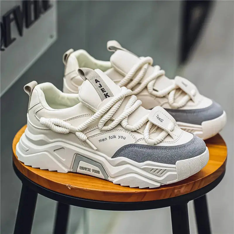 Simples Market men's casual sneakers, white low-top skate shoes with a chunky sole and gray toe cap, a pair on a wooden stool
