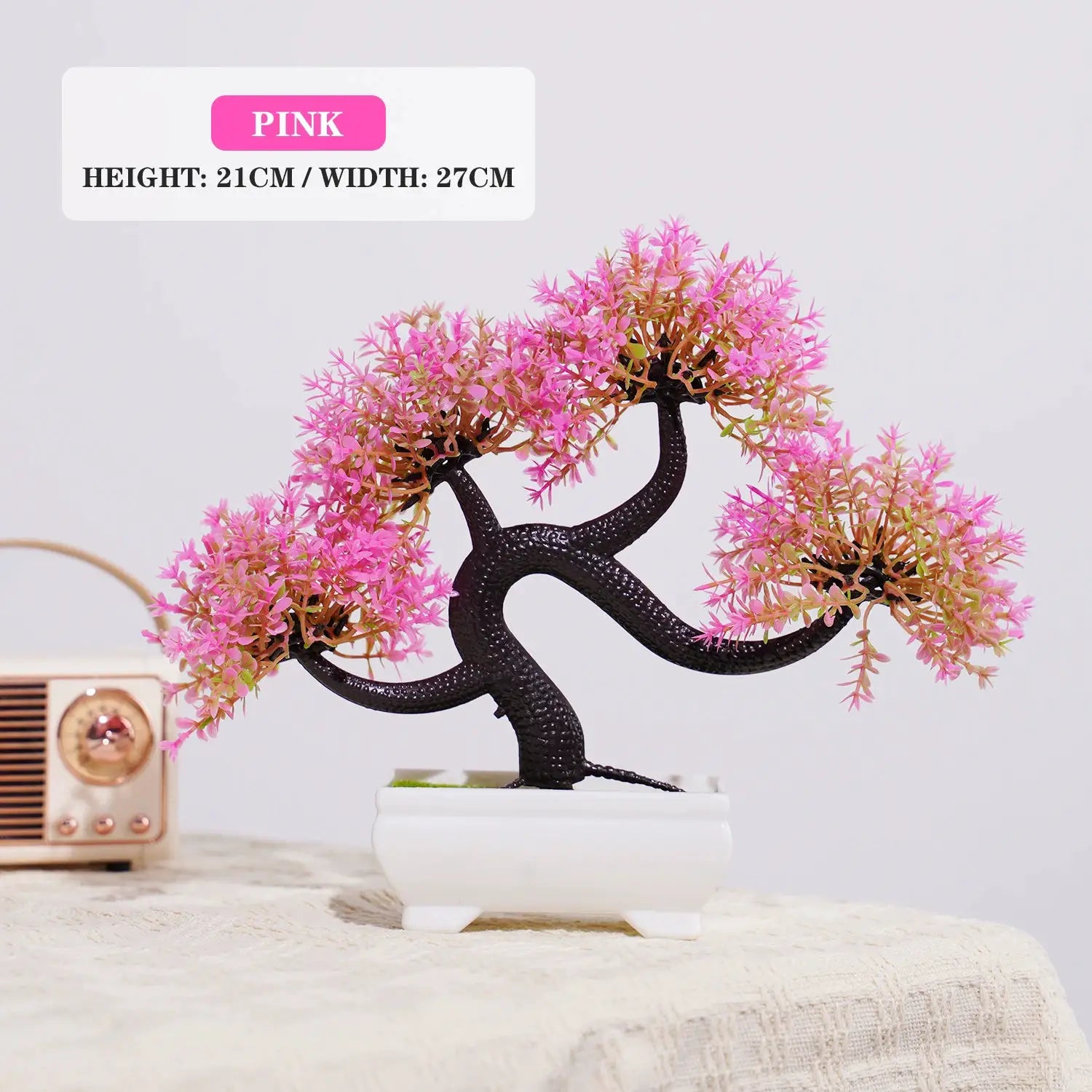 Pink artificial bonsai tree with a black twisting trunk in a white ceramic pot, tabletop decor