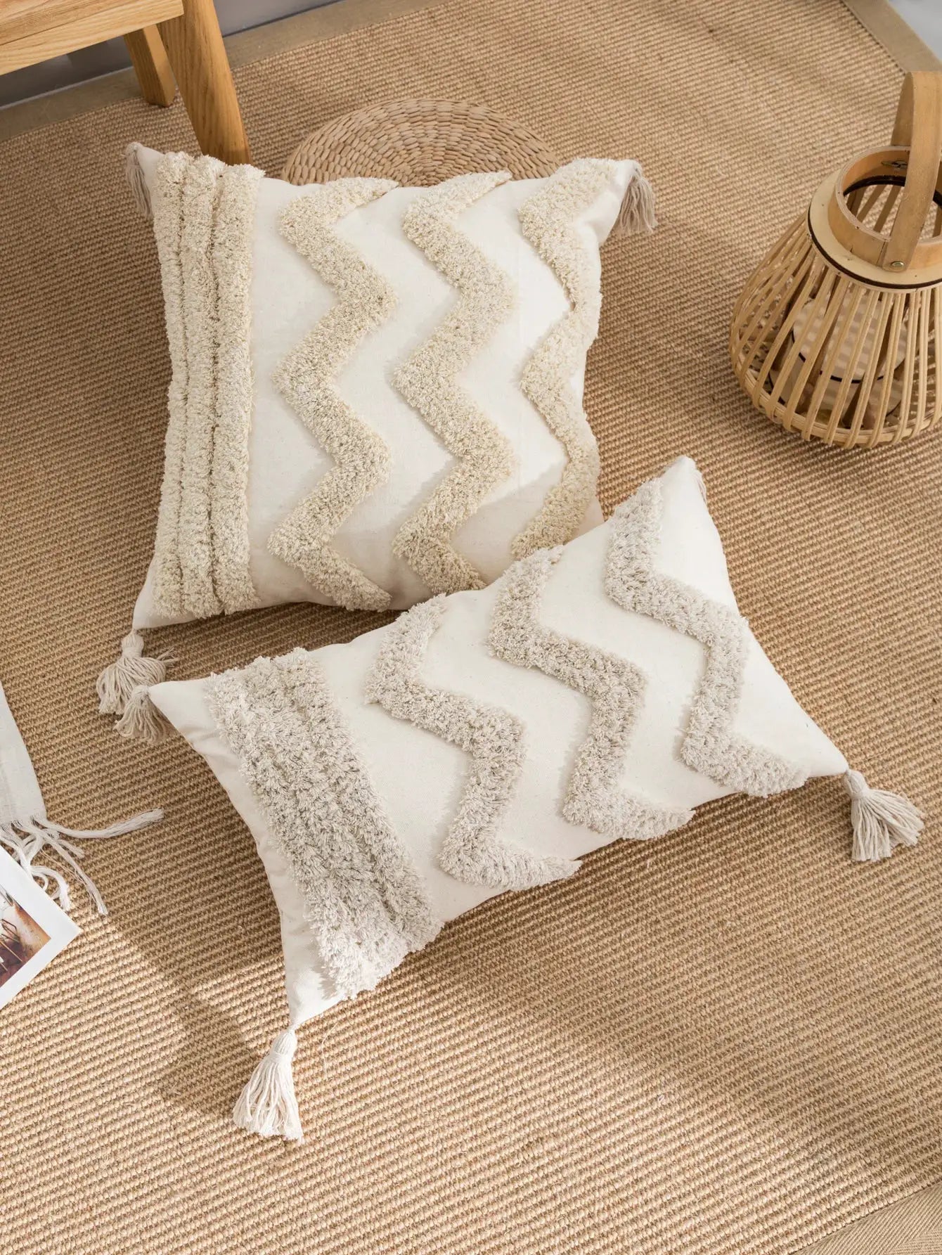 Two beige pillowcases with textured chevron pattern and tassel edges on a jute rug