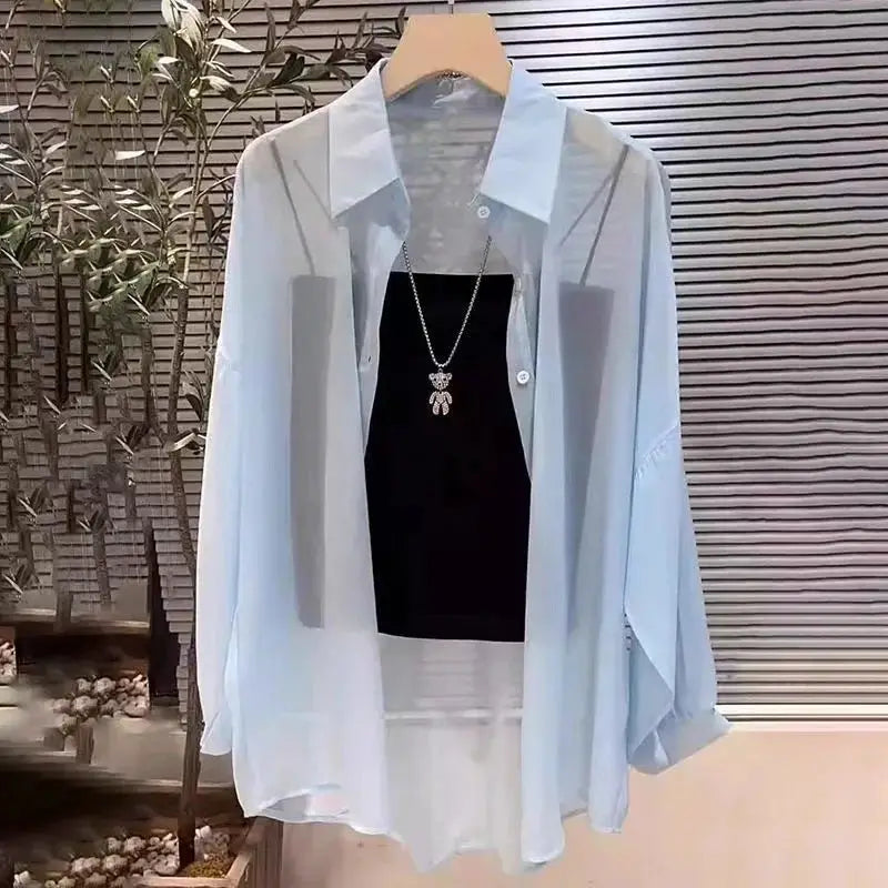 Plus-size light-blue sheer chiffon blouse with long sleeves and button-down front, layered over black top.
