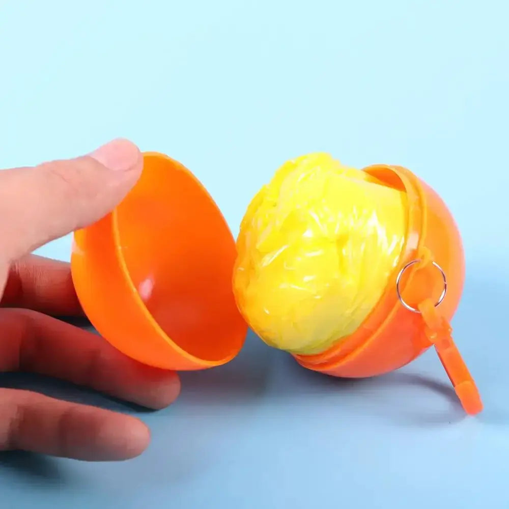 Portable disposable raincoat keychain compression ball, orange shell with yellow poncho inside by Simples Market