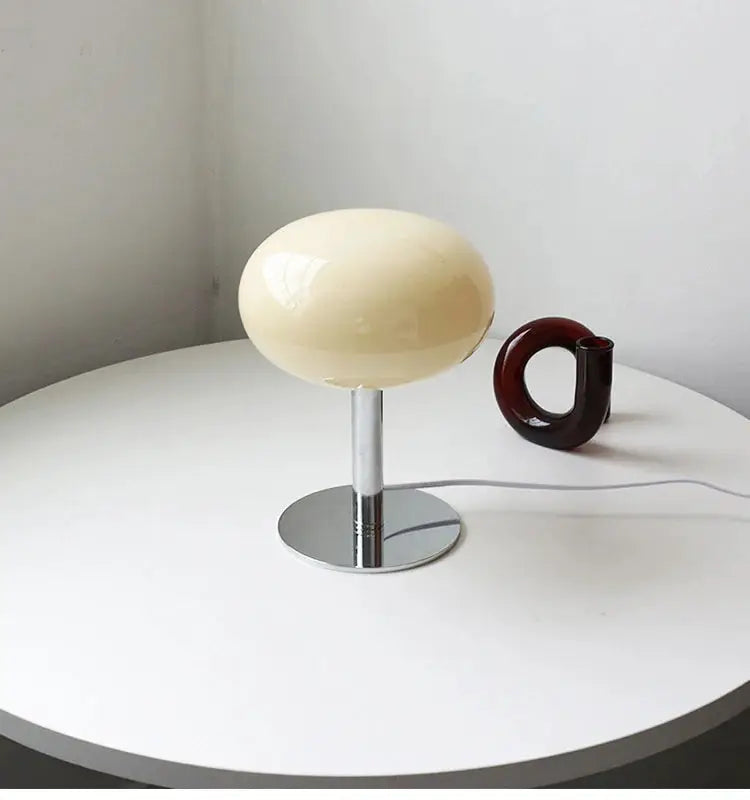 Macaron glass table lamp with chrome stem and beige shade for bedside or living room decor.