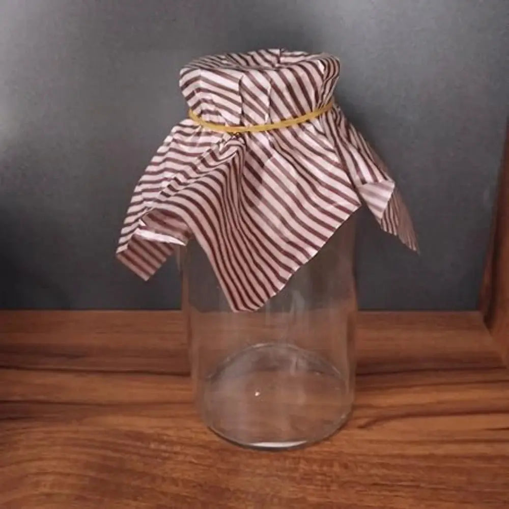 Yellow high-elastic rubber bands in a glass jar with striped cloth cover