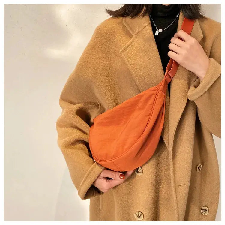 Casual nylon hobo crossbody bag in orange, worn over a camel coat