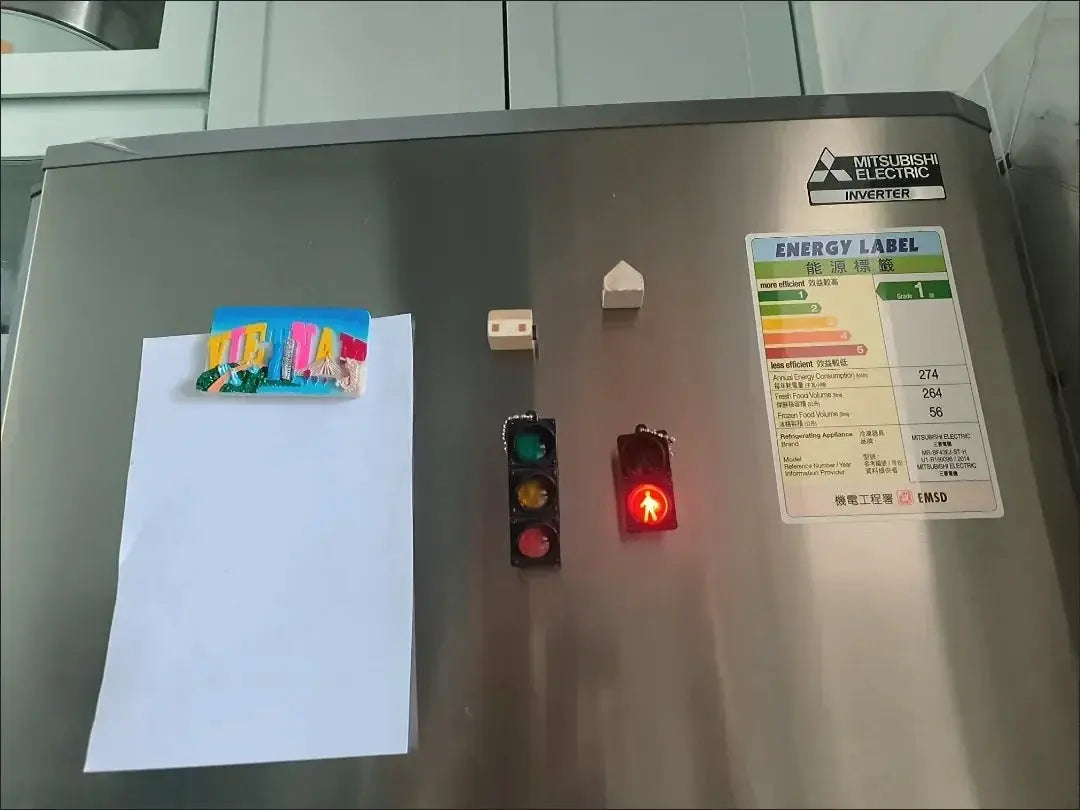 Traffic light magnetic refrigerator stickers; red pedestrian signal magnet on a stainless Mitsubishi Electric fridge.
