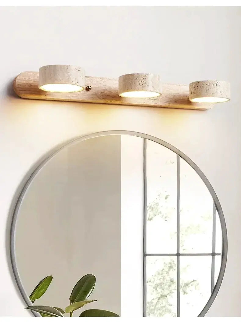 Round LED wall light with three concrete-style lamps on a natural wood backplate above a circular mirror